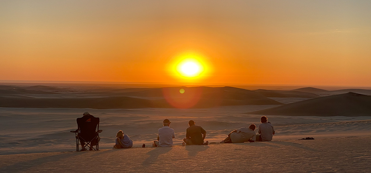 view of the sunset over the desert with people sitting in the foreground